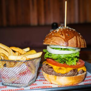 Mouthwatering cheeseburger with lettuce and tomatoes served with crispy fries.
