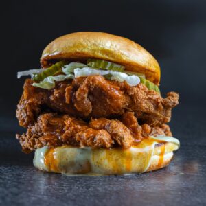 Delicious fried chicken burger topped with pickles and creamy cheese sauce.